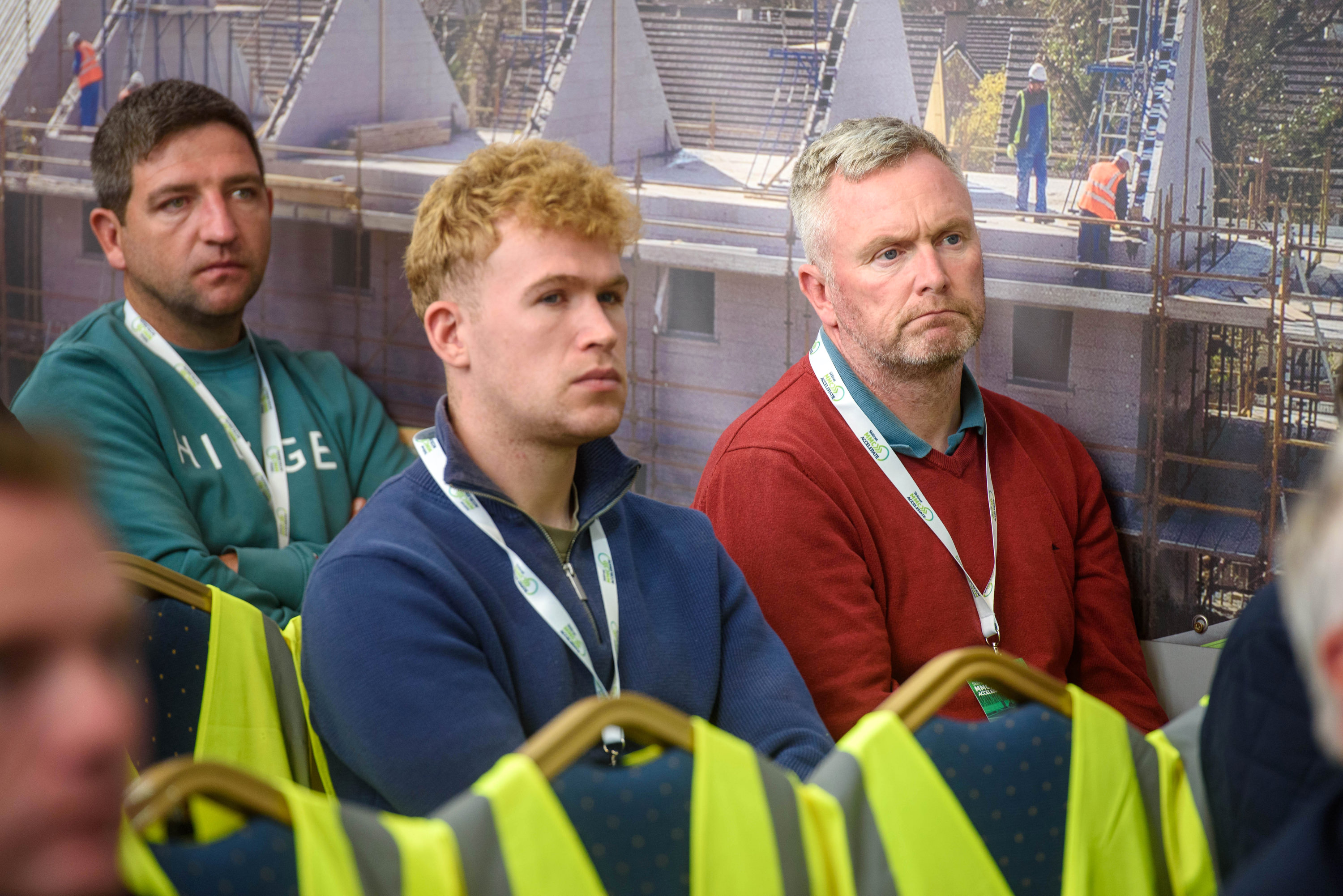 Three people wearing lanyards standing together at what appears to be an event or conference.