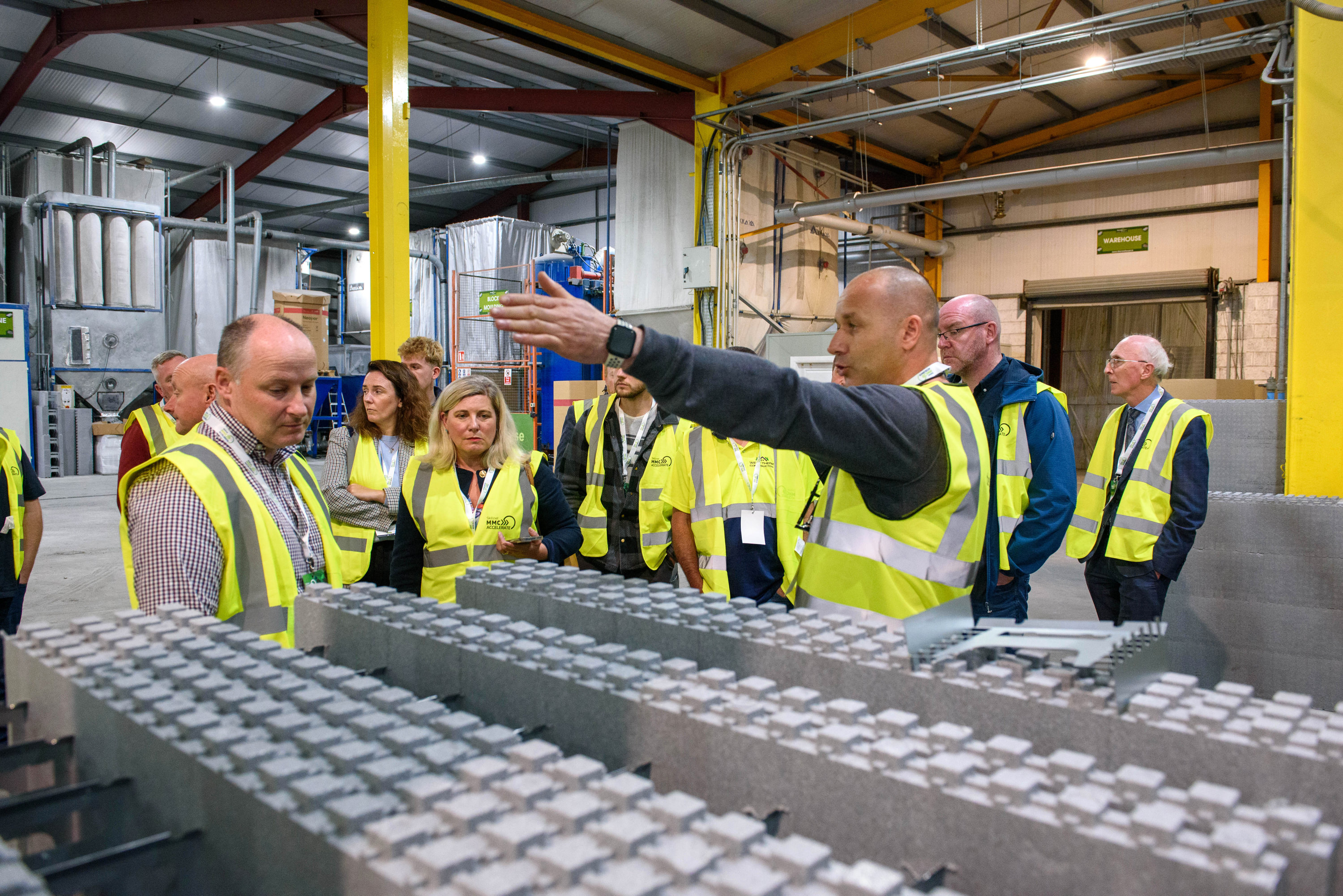 Group of workers in high-visibility vests inspecting an industrial assembly line.