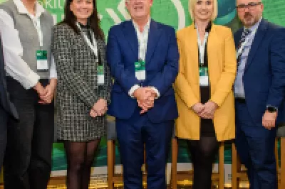 A group of people in smart clothing stand in front of a green screen.