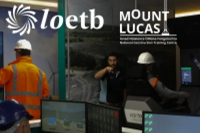 Four people in hard hats and high vis vets using computers in a room with computers and engineering equipment