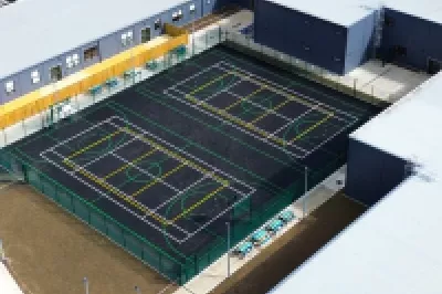 An overhead view of modern school U-shaped school buildings with two hockey courts in the centre.