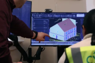 Two people in an office reviewing a 3D building model on a computer screen