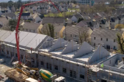 A large crane operating next to a number of houses under construction.
