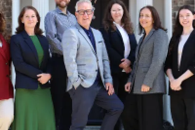 Group of seven people standing on the steps outside a building.