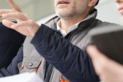A group of people in hard hats review building plans on large paper charts.