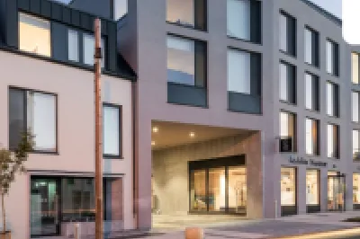 A modern multi-storey building with large windows and a sign reading "Ashlin House" on the facade