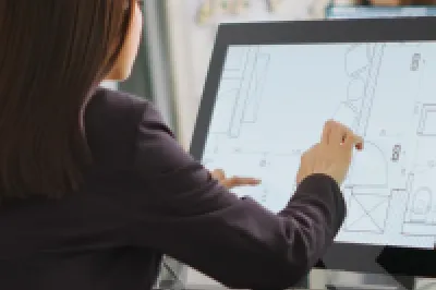 A person is seated in an office working on architectural design using a touchscreen device.