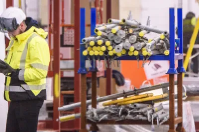 Workers in protective gear performing installation tasks inside an industrial facility