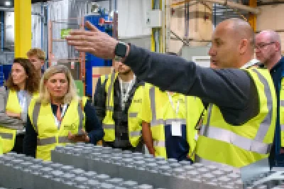 A group of people wearing high-visibility vests during a guided tour inside an industrial facility.
