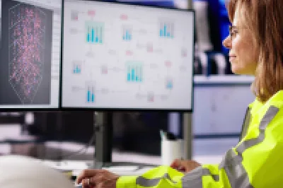 Engineer in a high-visibility jacket monitoring industrial process dashboards