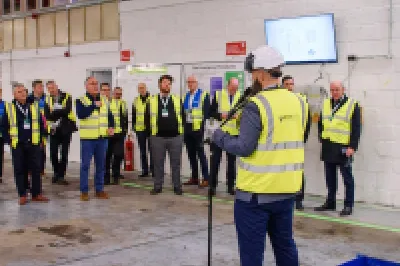Workers in high-visibility vests gathered in an industrial warehouse space for safety training.
