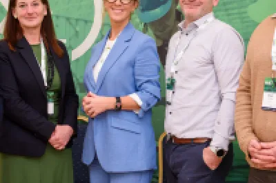 Five people standing together in front of a green Skillnet MMC Accelerate event banner, facing the camera and smiling.