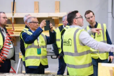 Workers in yellow safety vests on a production line in an industrial facility.
