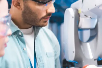 Two researchers examining a robotic arm in a laboratory setting.
