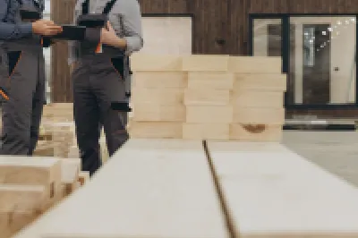 Two people examining lumber in a woodworking workshop or construction site.