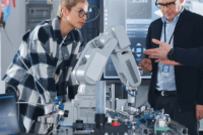 Three people examining robotic equipment in a bright laboratory setting.