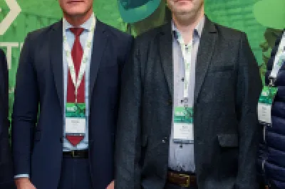 Four businessmen in suits standing together against a green backdrop with Fortinet logo.