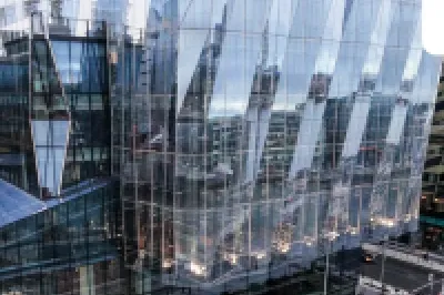 Modern glass office building beside a historic red brick structure on a city street.