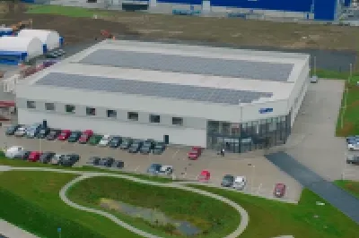 Aerial view of a modern industrial or logistics park with large blue warehouses and well-maintained roads.