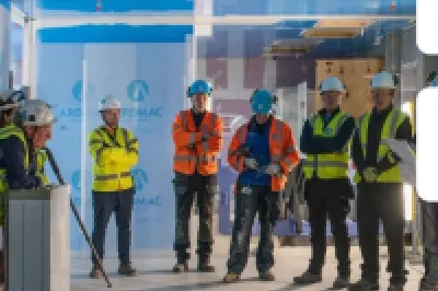 Group of workers in high-vis vests and hard hats during a facility tour, with Ardmac and Rockwell logos.