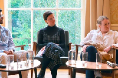 Five people seated in a semicircle having a panel discussion in an elegant, warmly lit room.