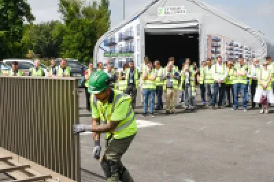 Workers in safety vests and hard hats gathered outdoors at an industrial facility during a demonstration.