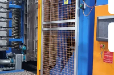 Industrial manufacturing machine in blue and orange with BuildBlock logo in upper right corner.