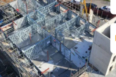 Aerial view of an active construction site with steel framework, featuring Clancy and Remagin logos.