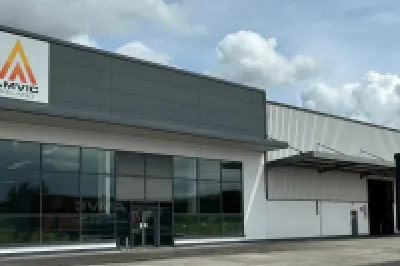 Modern commercial building with yellow triangle logo, large windows, and a truck parked outside.