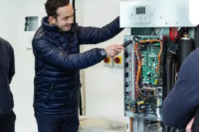 Three men examining an open heat pump unit during a Pipelife training session.