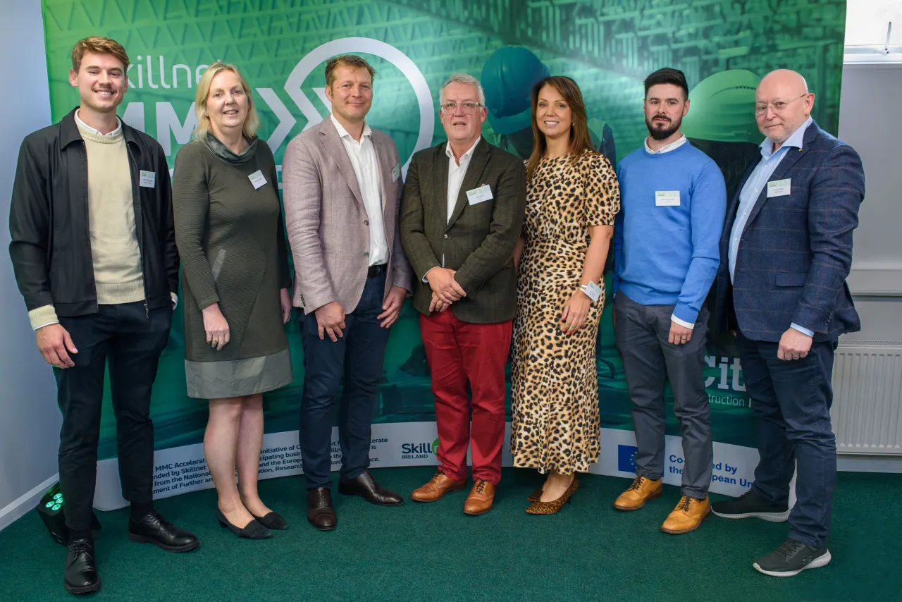 A group of people standing together against a green backdrop at an event.