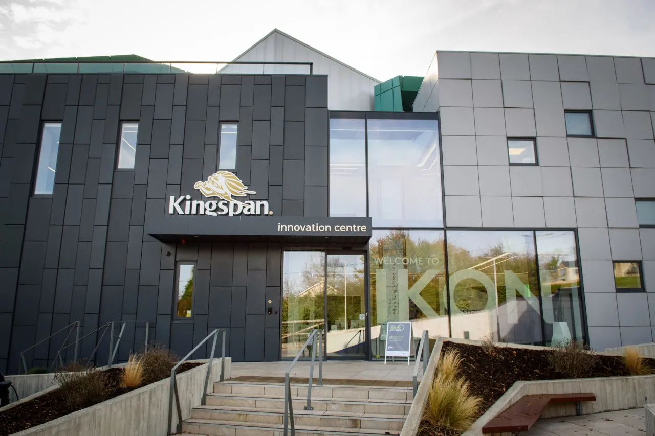 Modern gray building entrance with "Kingdom" signage and a green crown logo.