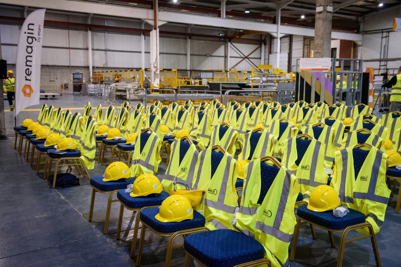 Yellow high-visibility safety vests neatly arranged in rows at a warehouse or manufacturing facility.