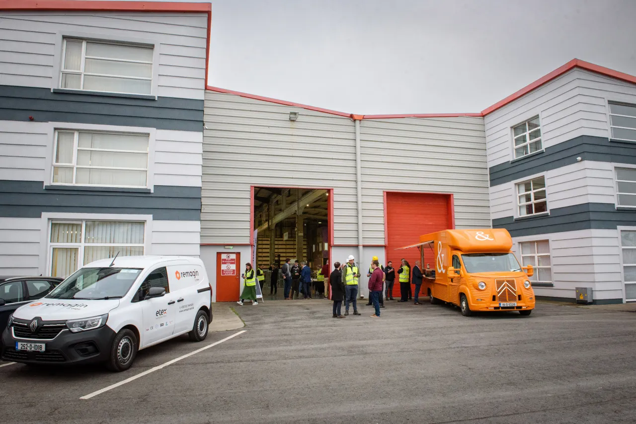 Modern warehouse facility with white vans and orange truck parked outside.