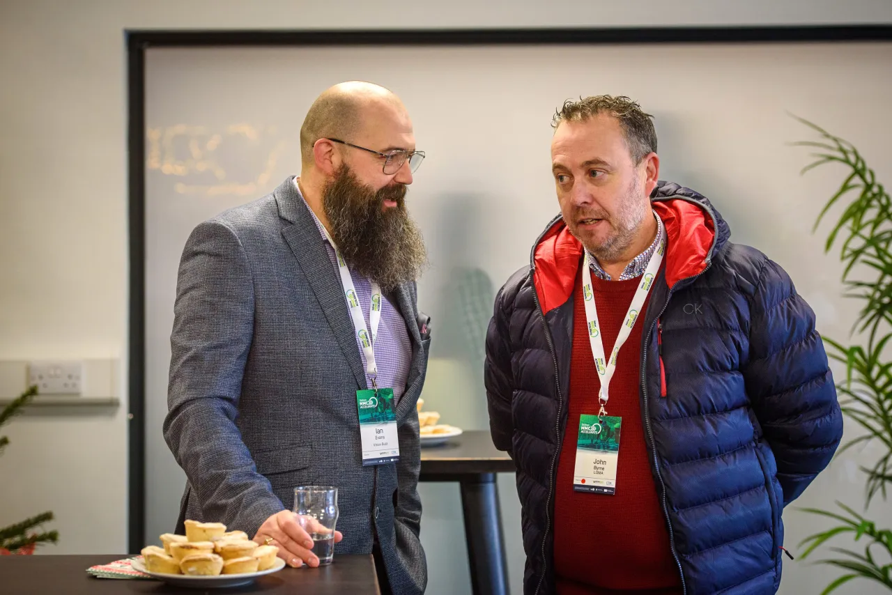 Two people standing together at what appears to be a conference or event, wearing lanyards.