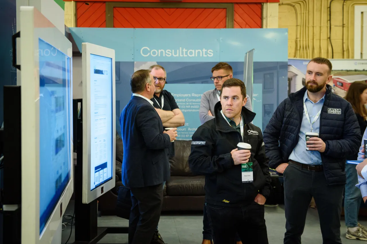 People examining digital display screens at a business exhibition or trade show event.