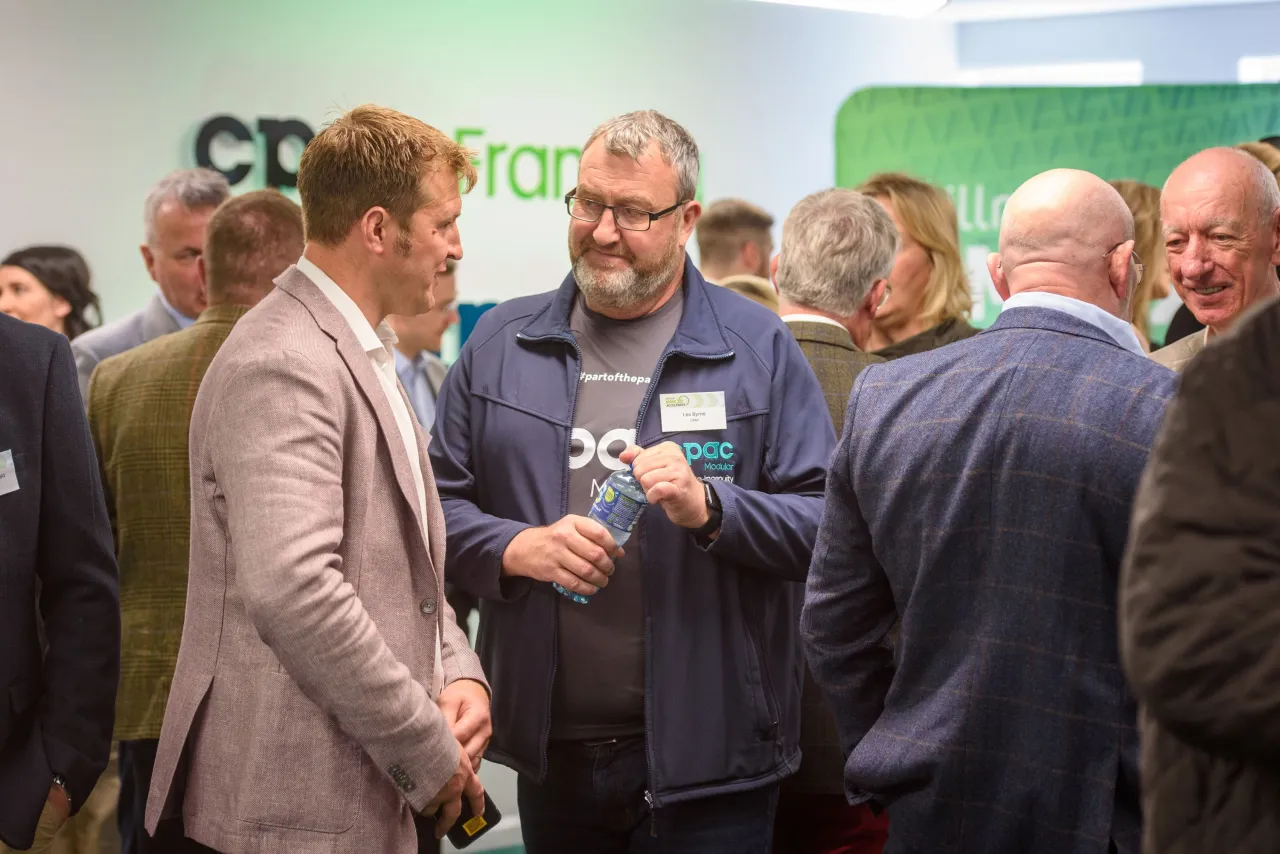 A group of people networking at a professional event with a CDP sign visible in the background.