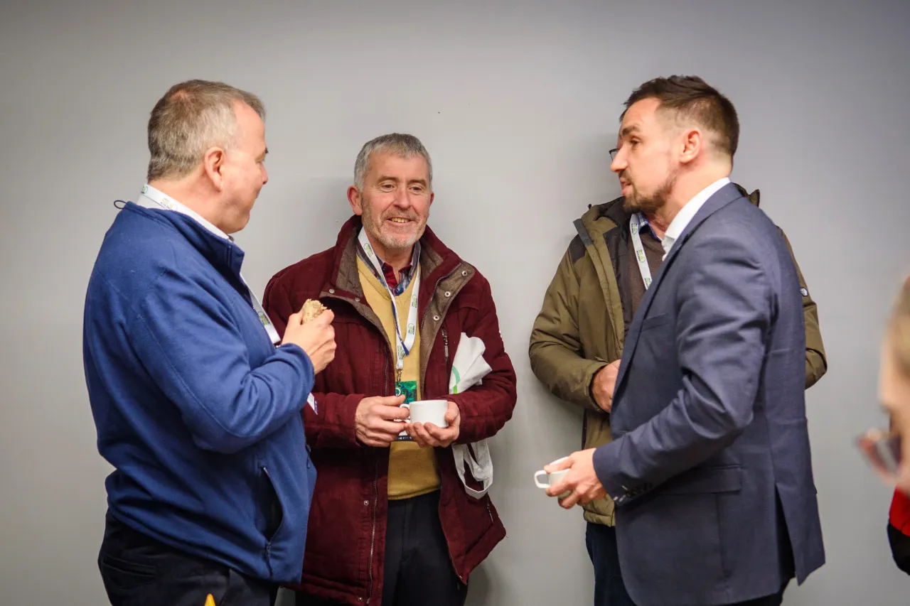 Three people in business attire conversing at a networking event.