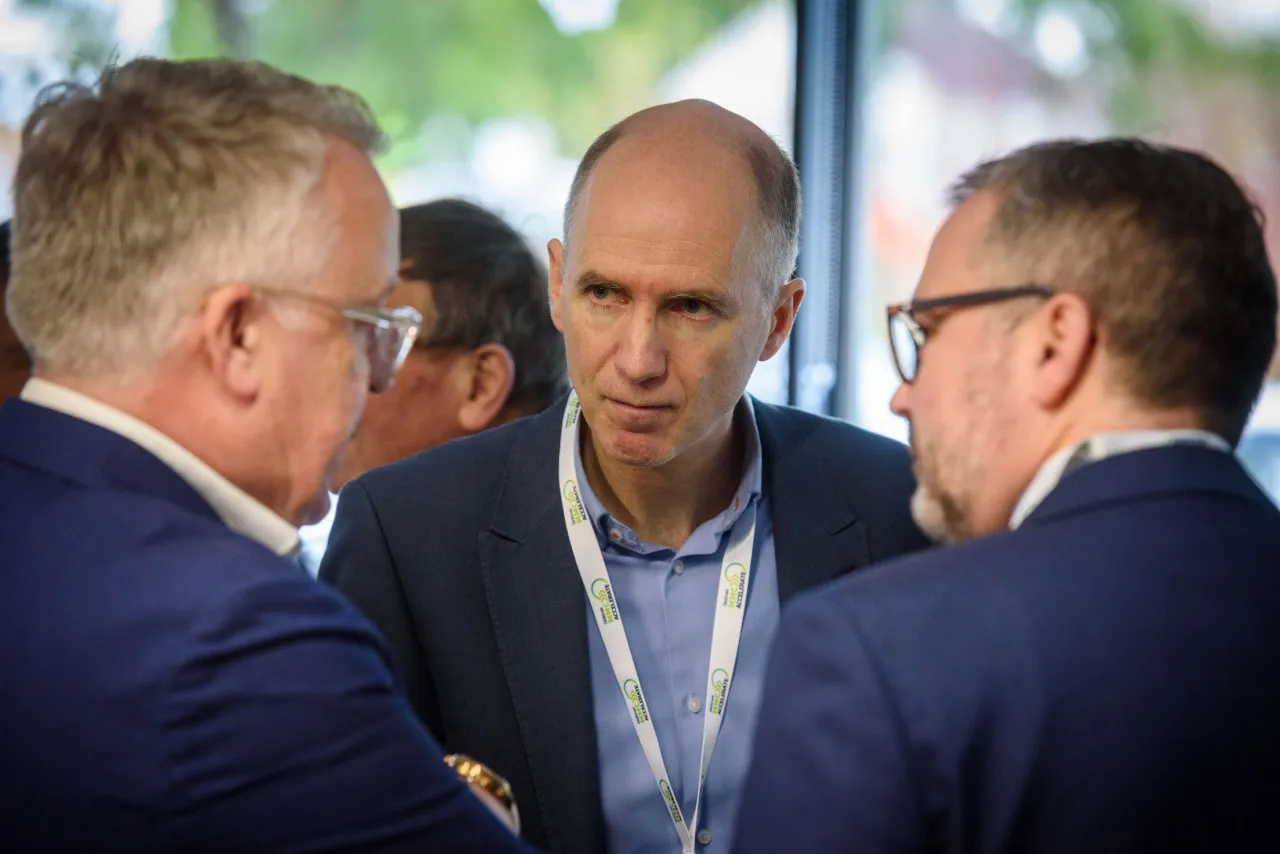 Three professionals in suits engaged in a focused business conversation.