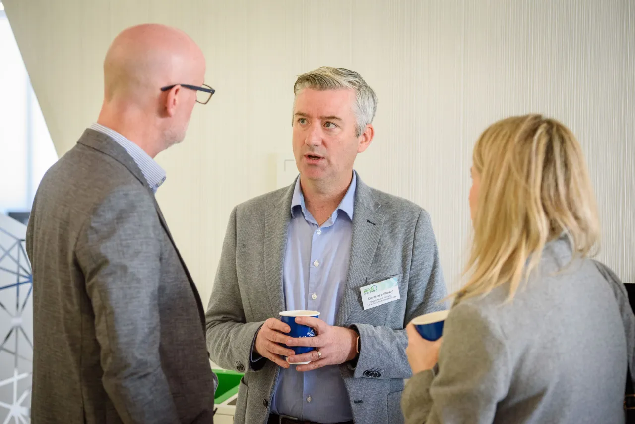 Three people in business attire having a conversation at a networking event.