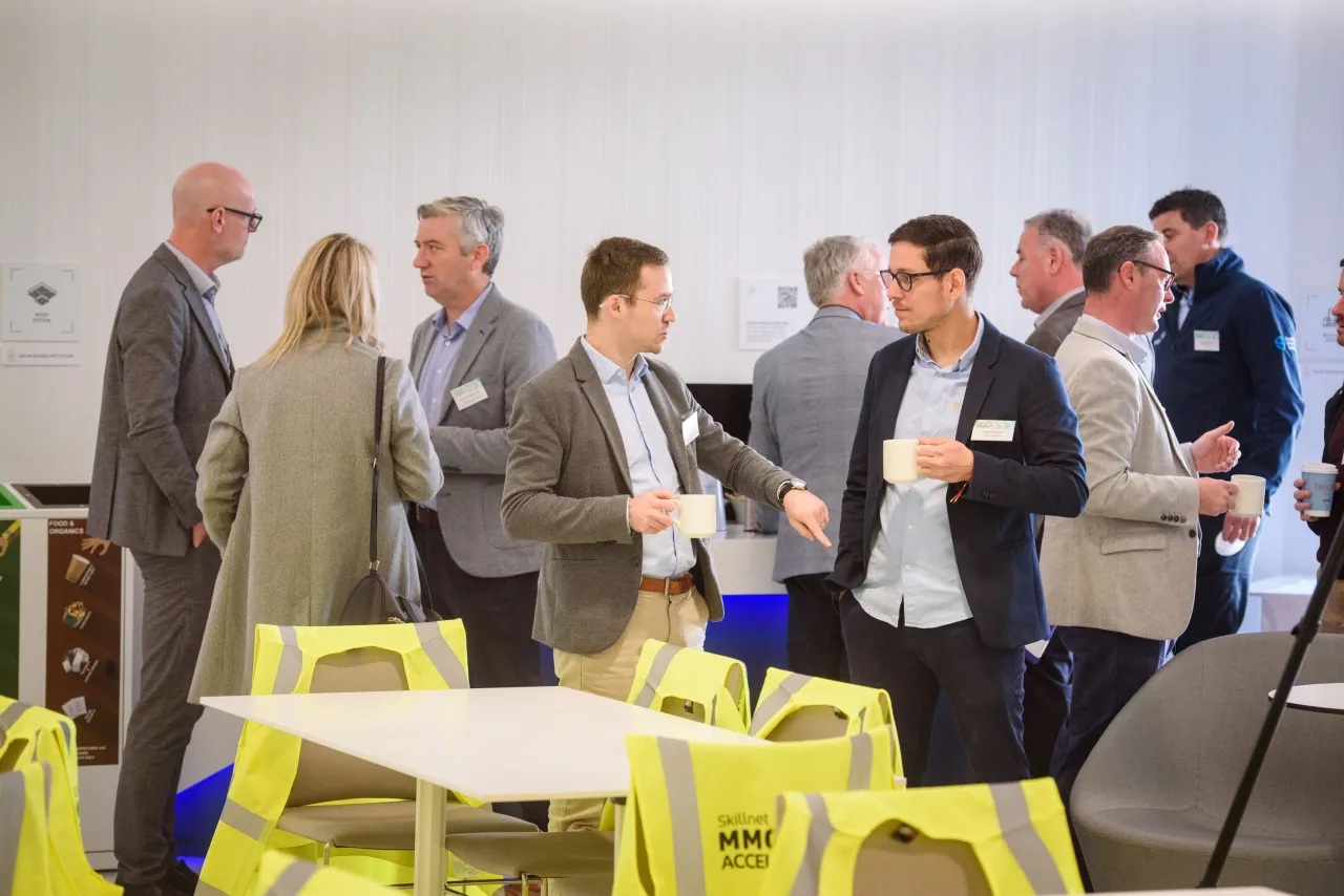 Group of people networking in a bright office space with yellow chairs.