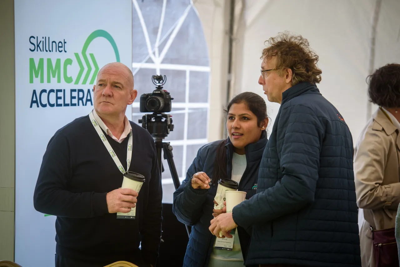 A group of people standing at a networking event with a Stinar MMCF Accelerate banner visible.