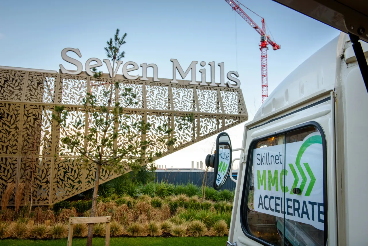 Large stone sign reading "Steyn Mills" in front of a construction site with a work vehicle visible