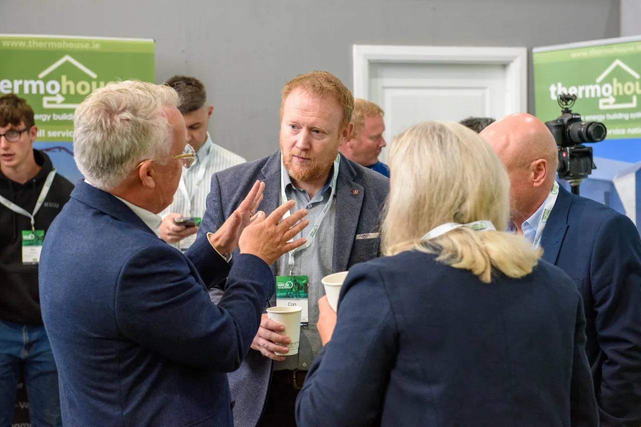 A group of people in business attire engaged in conversation at a networking event.