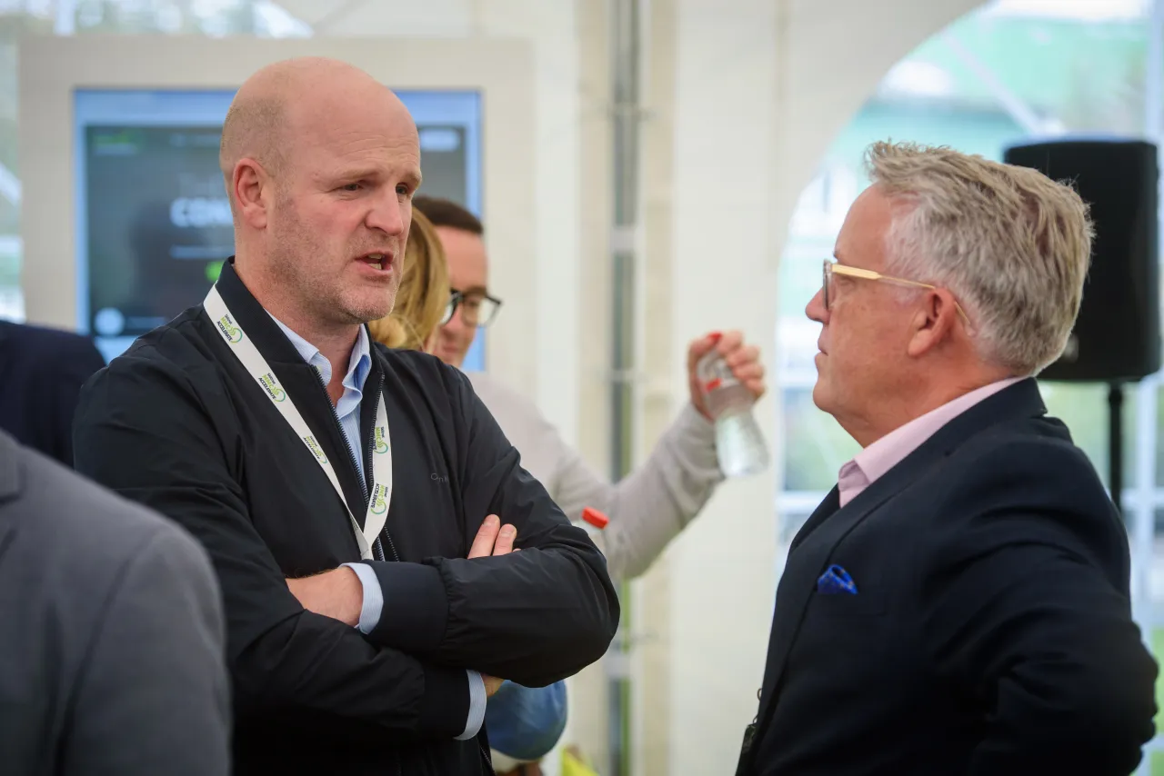Two men in suits having a conversation at a formal event.