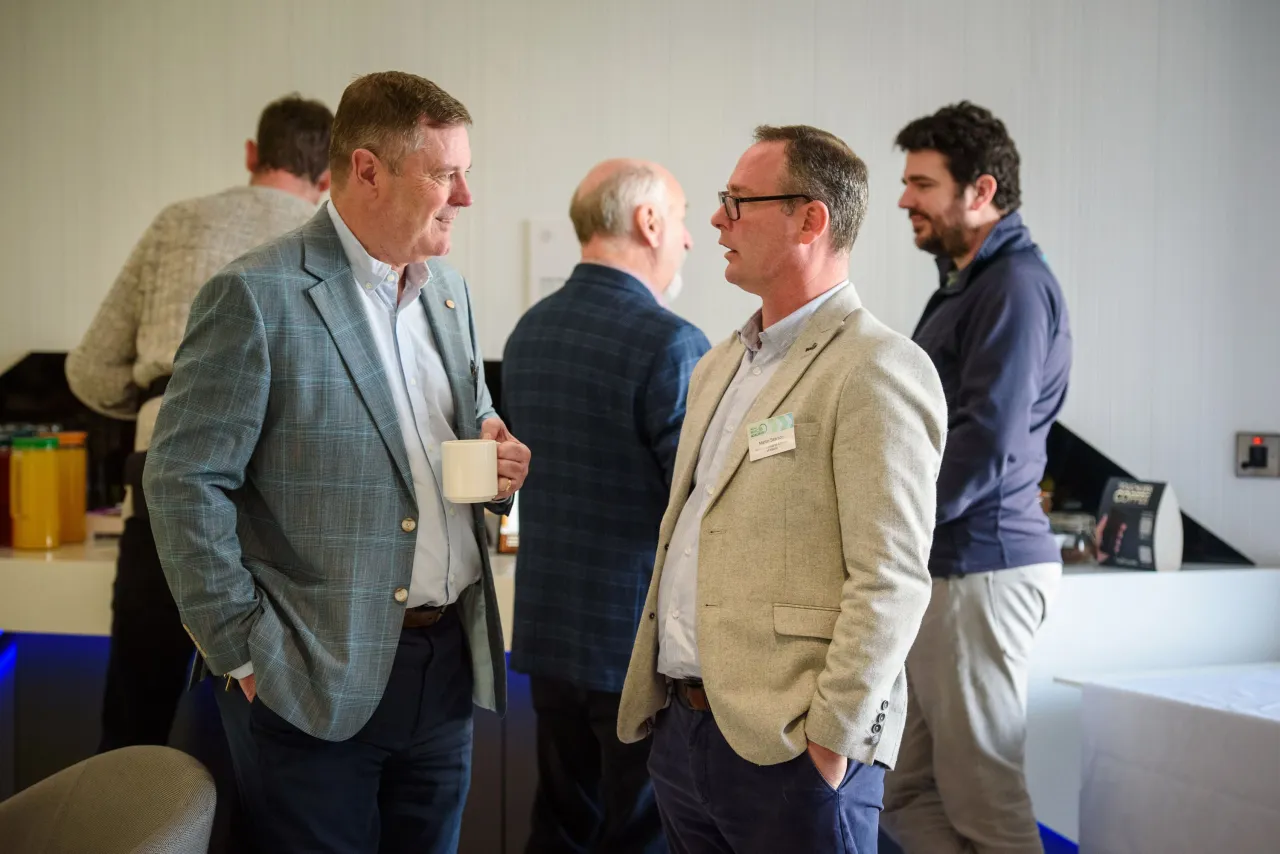 Group of well-dressed men conversing at an indoor professional event.