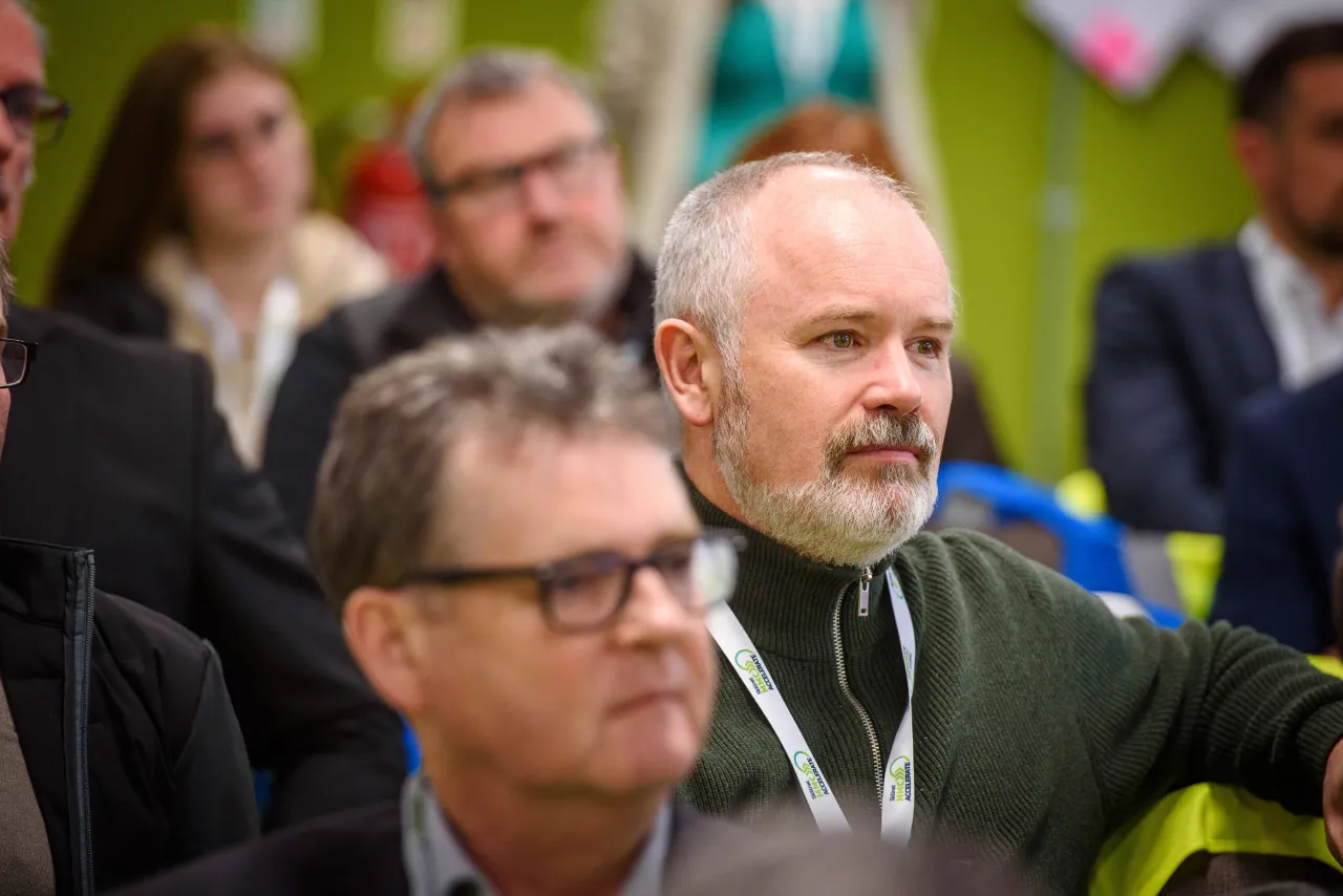 A group of people at a business conference with green accents in the background.