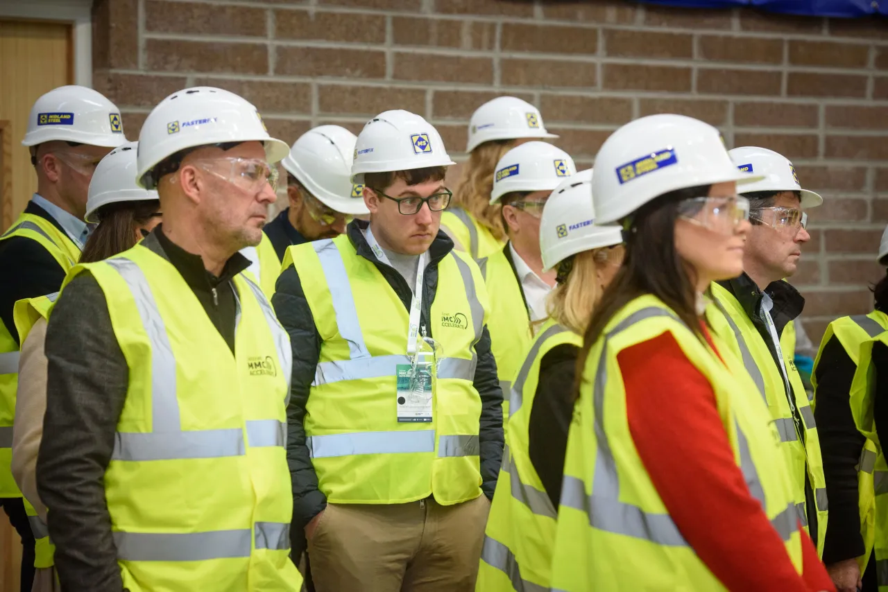 Group of construction workers wearing white hard hats and high-visibility safety vests on a building site.