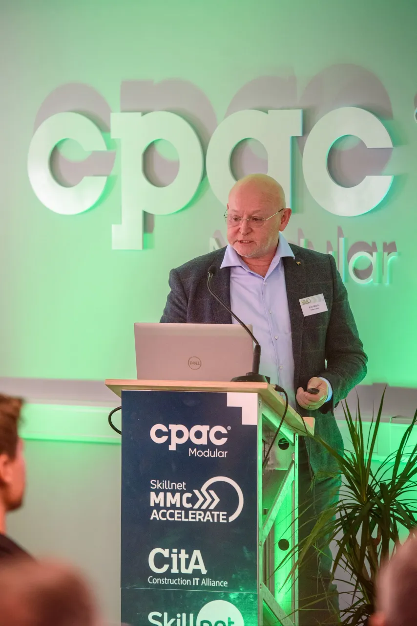 A person in formal attire speaking at a podium with "cpac" logo displayed on green background.