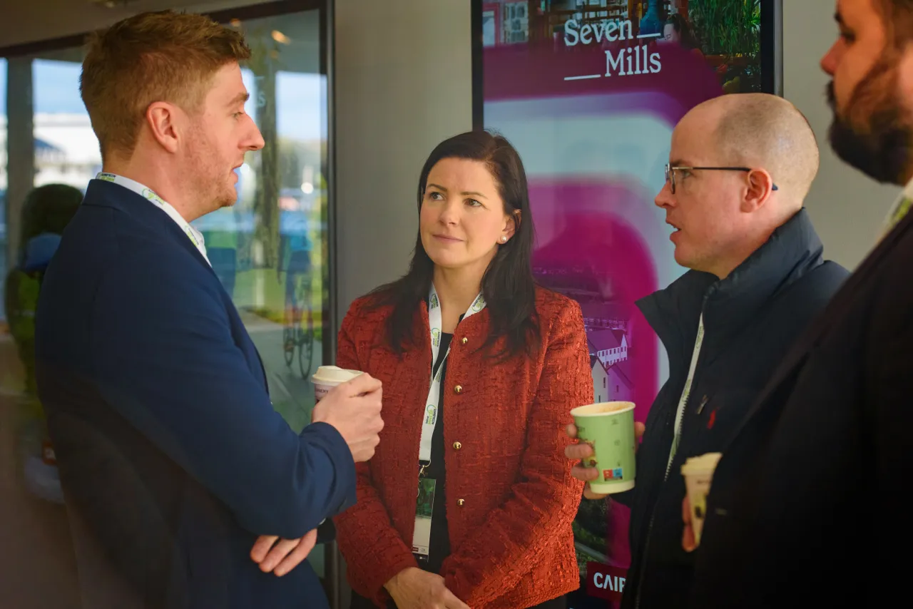 Three people in formal attire engaged in conversation in an indoor setting.